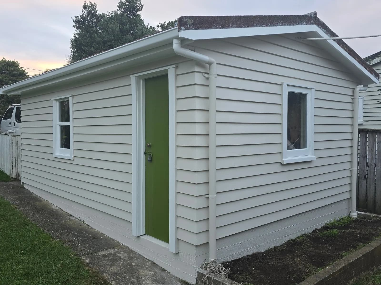Small weatherboard studio painted white with a bright green door