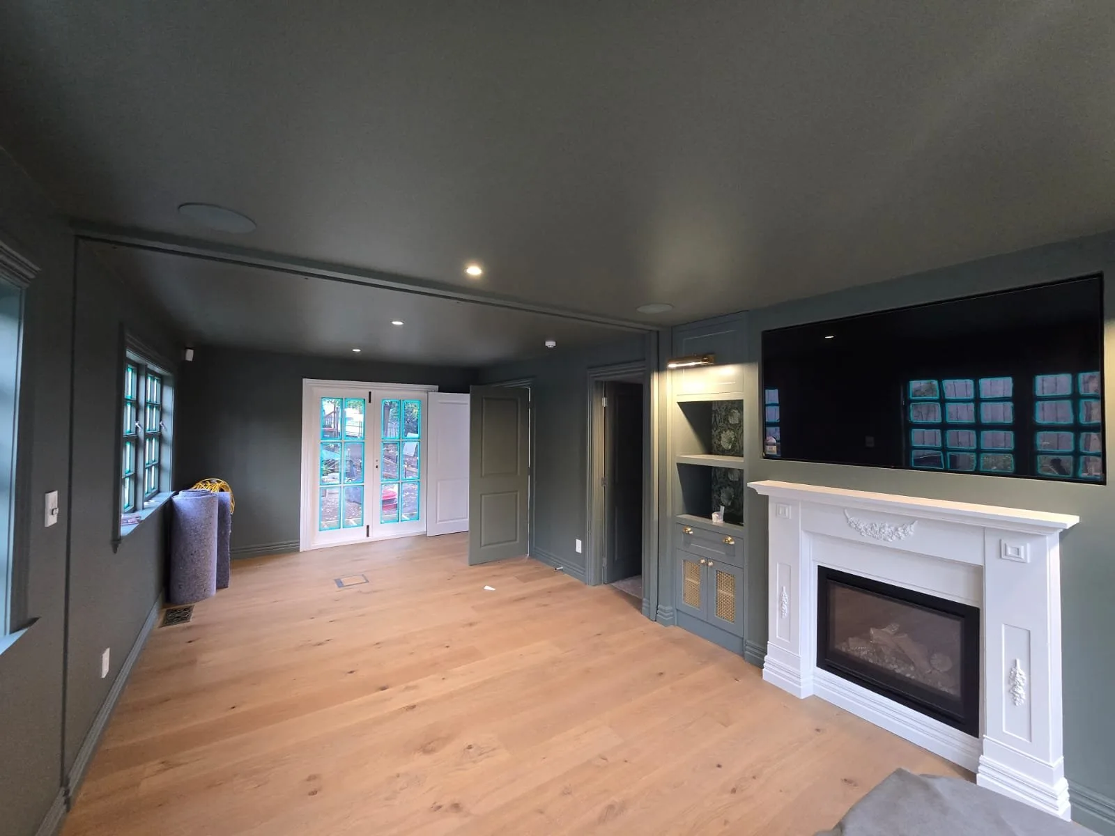 Lounge painted dark green with a white fireplace surround and oak floor
