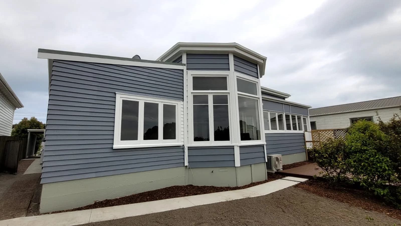 Grey weatherboard home with white window trim and a bay window after an exterior repaint