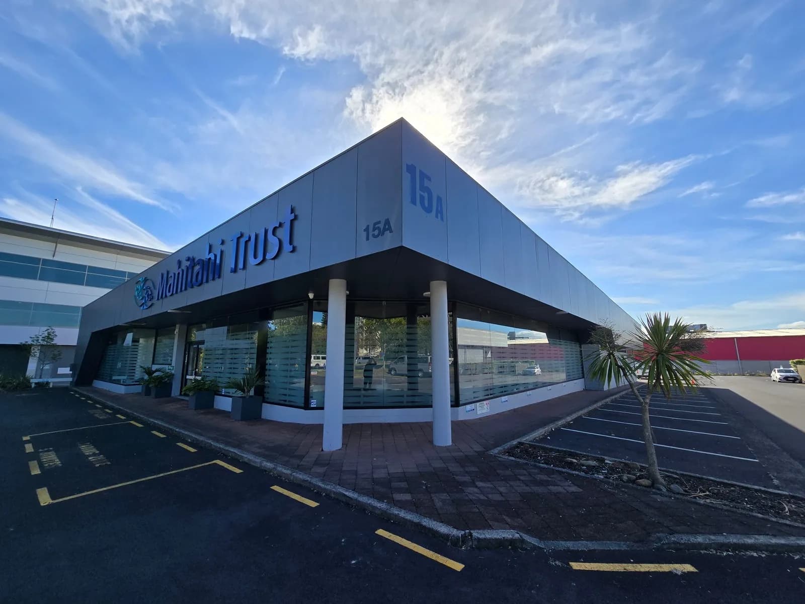 Repainted commercial building with signage and a covered entrance, seen from the car park on a clear day