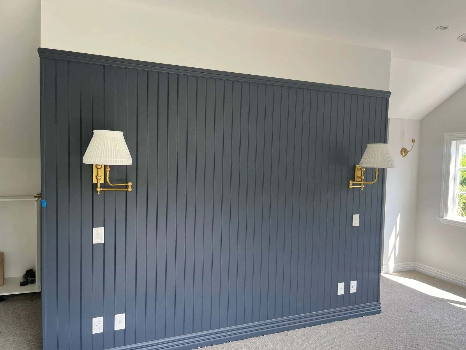 Navy painted tongue-and-groove feature wall with two brass wall lights