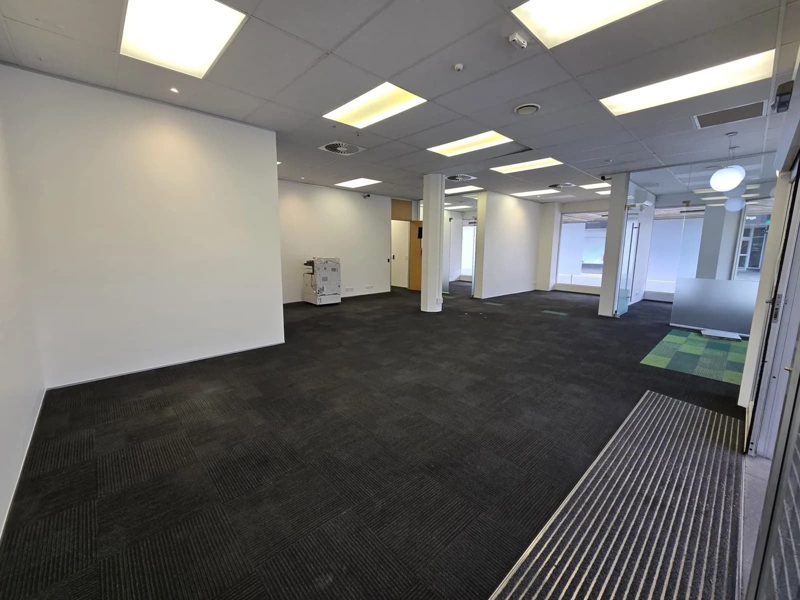 Empty office floor with freshly painted white walls and columns, ceiling tiles and dark carpet