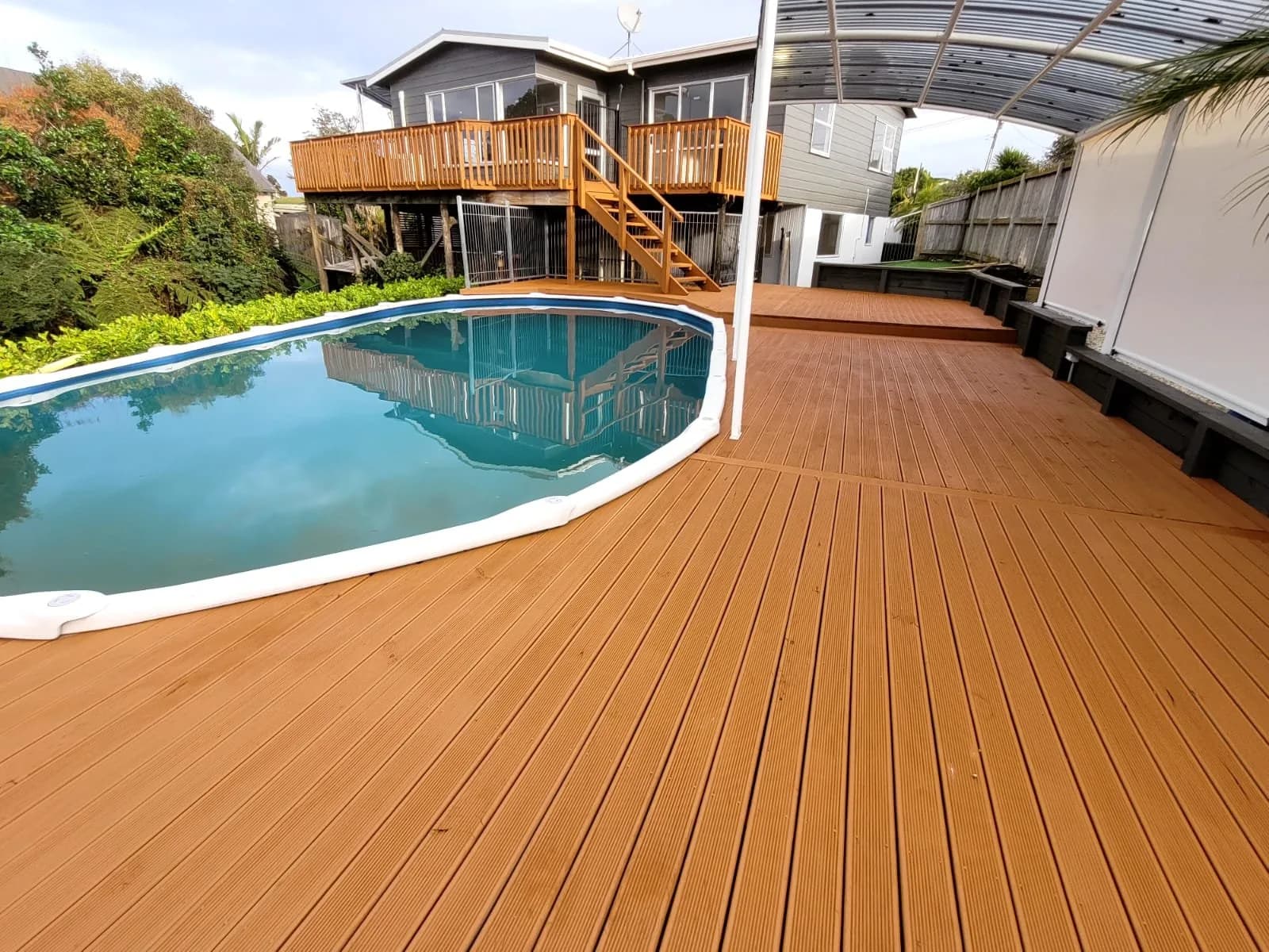 Stained timber deck curving around a swimming pool