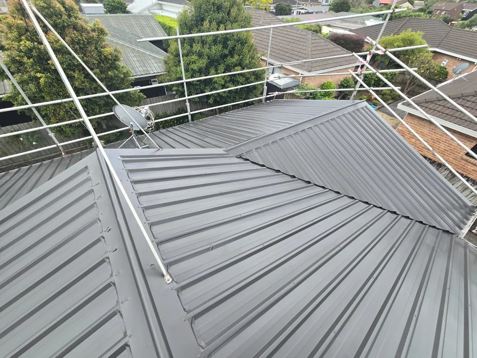 Long-run steel roof freshly painted grey, with edge protection in place