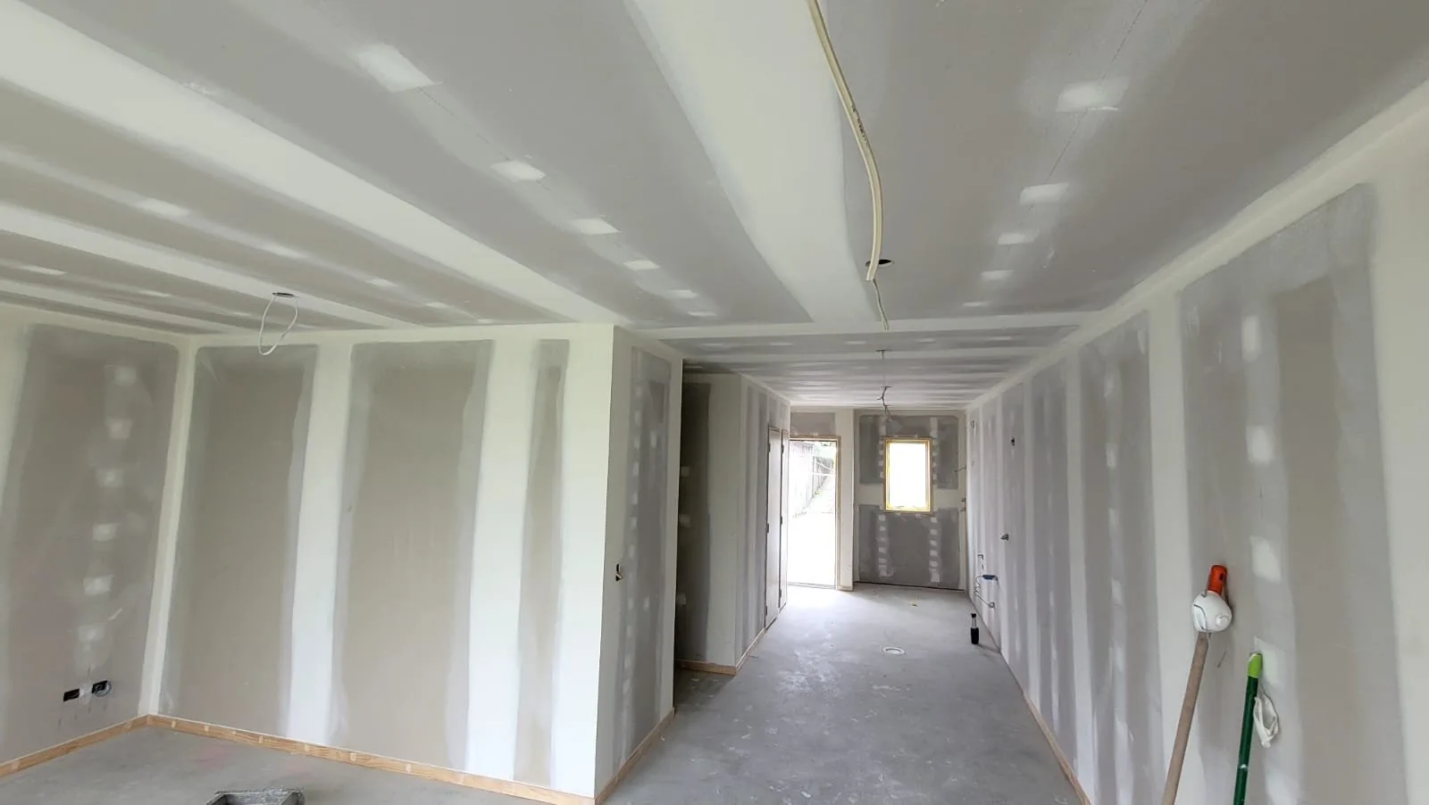 Long corridor lined with plasterboard, joints and screw heads stopped on the walls and ceiling