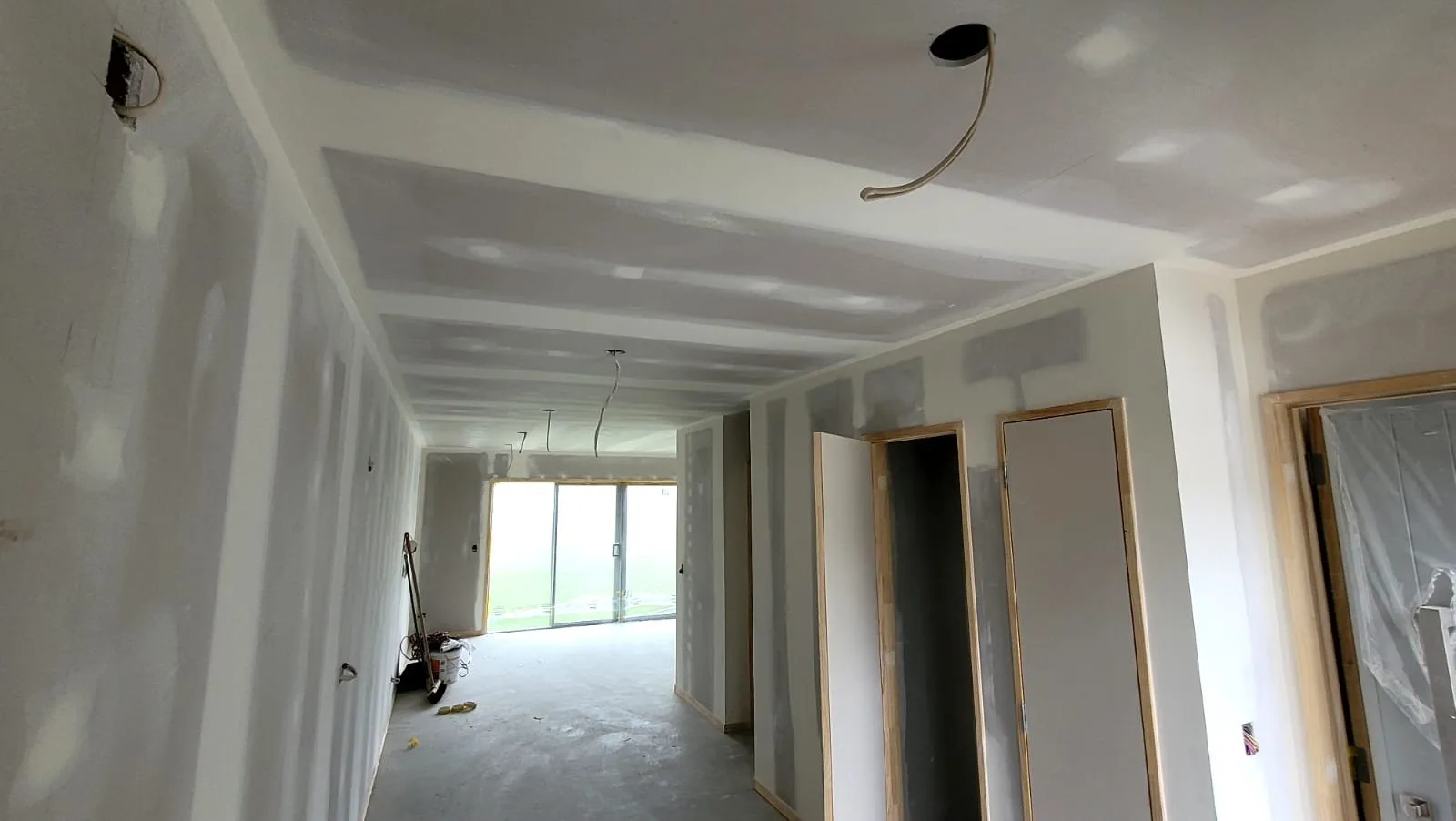 Freshly lined hallway with the first coats of stopping on the wall and ceiling joints, doors hung and ready for the next coat