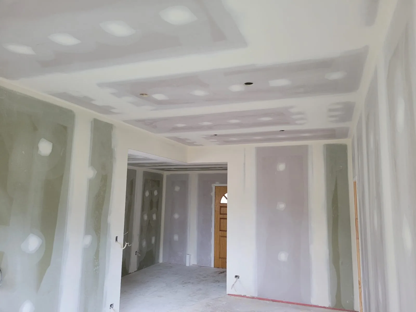 Open-plan room part way through GIB stopping, every joint taped and coated and the screw heads filled, ready for the next coat
