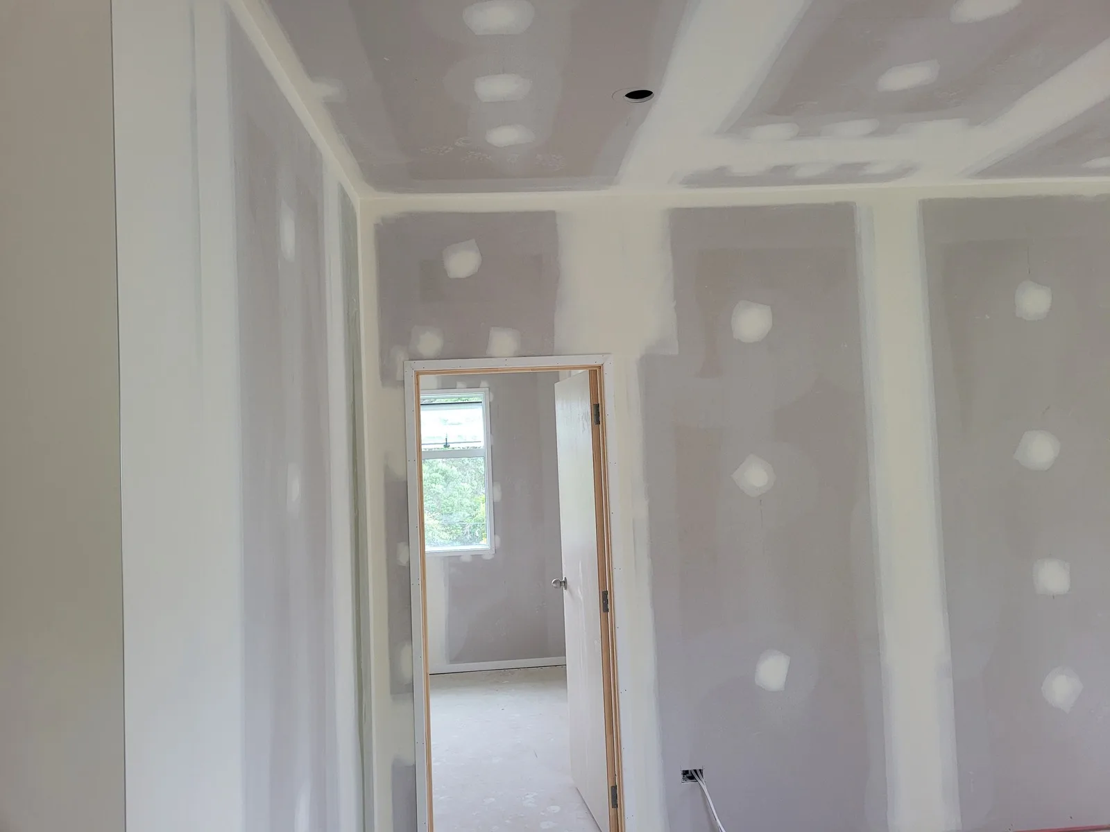 Bedroom and doorway lined in plasterboard with the joints and screw heads stopped on the walls and ceiling