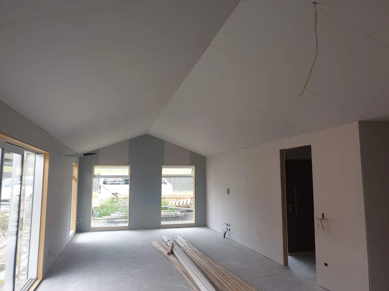 Room with a raked ceiling newly lined in plasterboard, the first coat on the joints and timber trim on the floor