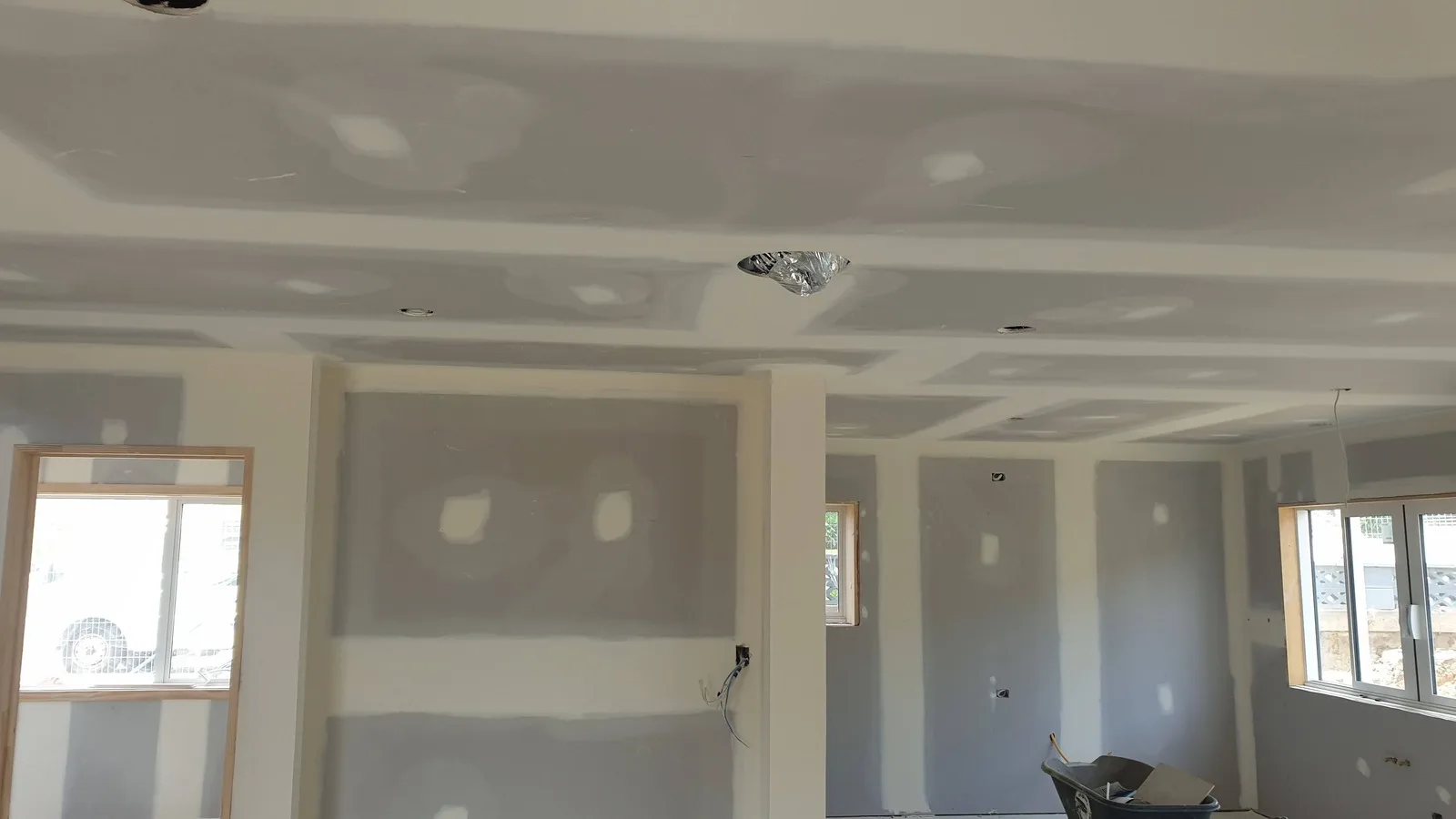 Open-plan room lined in plasterboard, with every joint and screw head on the walls and ceiling stopped